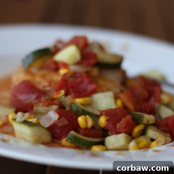 plate of piece of mahi mahi covered with tomatoes, zucchini, and corn