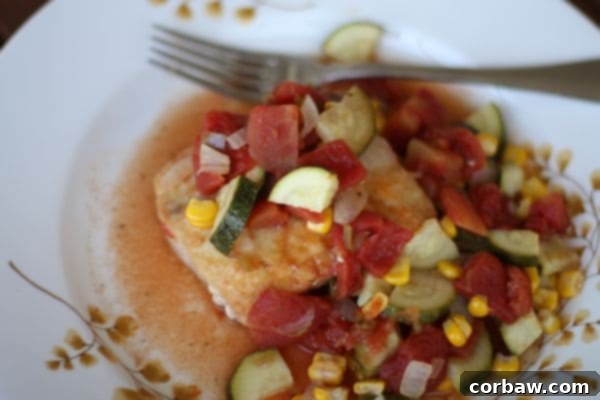 plate of piece of mahi mahi covered with tomatoes, zucchini, and corn