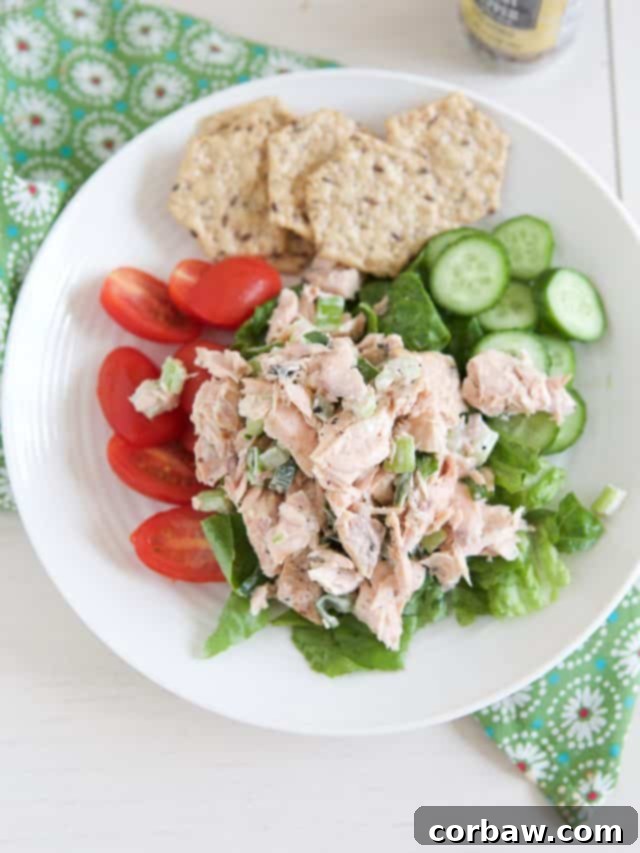 Simple & Satisfying Salmon Salad 3 white plate filled with lettuce, tomato and cucumber topped with salmon salad and crackers on side