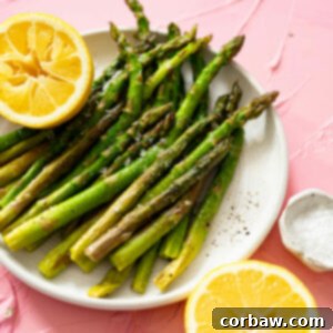 Mastering Steak Sides: 20+ Perfect Pairings and Pitfalls 9 Perfectly cooked sous vide asparagus spears on a white plate with lemon wedges.