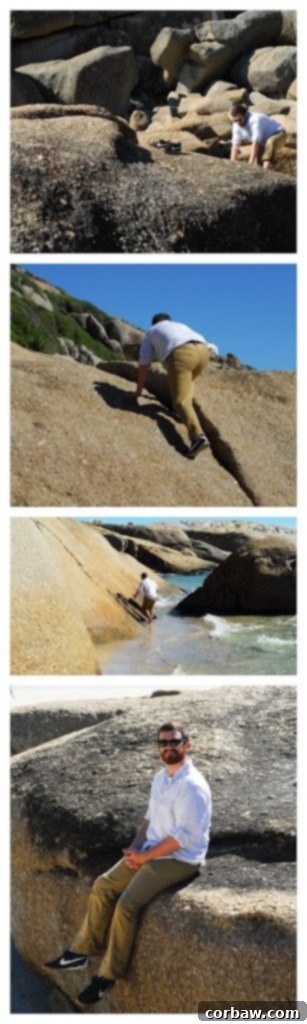 A person standing atop a large boulder, looking out at the ocean.