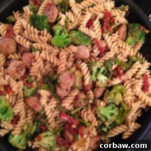 A close-up of a rustic dish of Whole Wheat Pasta with Italian Chicken Sausage, Broccoli, and Sun-Dried Tomatoes, ready to be served.