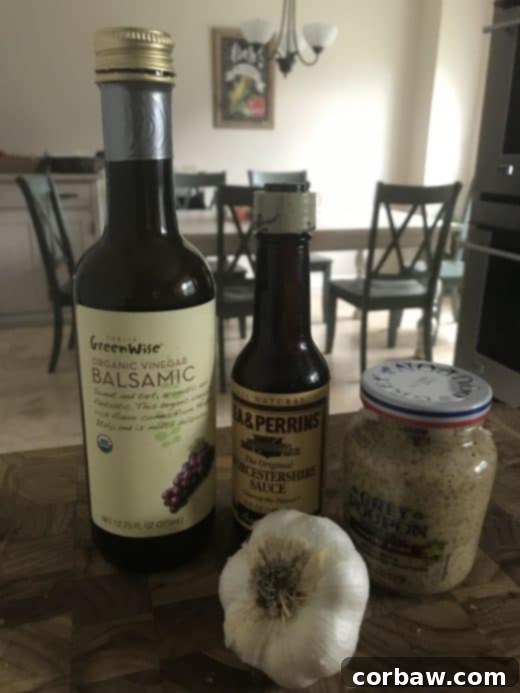 ingredients for london broil marinade including balsamic vinegar bottle, worcestershire sauce bottle, jar of grey poupon country dijon and bulb of garlic