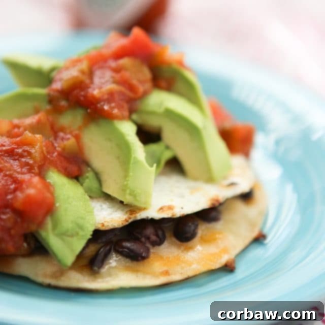 Crispy Black Bean and Egg Tostadas 4 Overhead view of two Black Bean and Egg Tostadas on white plates, garnished with fresh avocado slices and cilantro, highlighting their appetizing appearance.