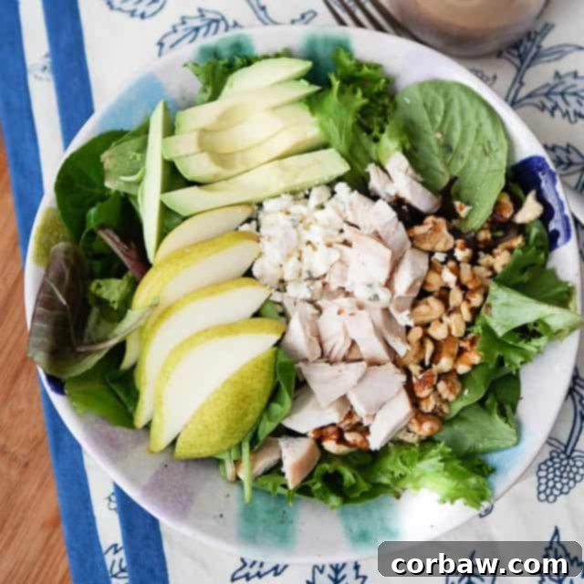 Avocado, Pear, and Chicken Salad 3 overhead photo of salad plate with greens, sliced pear, sliced avocado, chopped rotisserie chicken and walnuts
