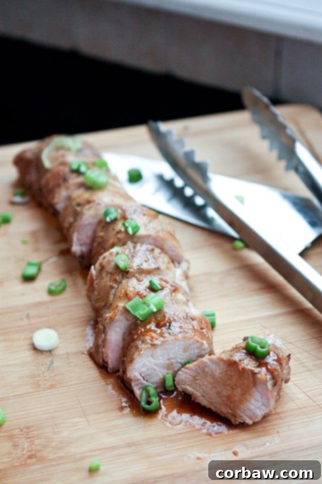 Juicy Asian Citrus Pork Tenderloin Close-up of sliced Slow Cooker Asian Citrus Pork Tenderloin, showcasing its juicy texture and rich sauce, garnished with fresh green onions.
