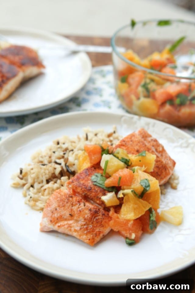Blackened Salmon with Citrus Salsa is the perfect balance between spicy and sweet. Simple to prepare and makes a fresh, light dinner perfect for weeknights! Recipe via aggieskitchen.com portion of blackened salmon topped with citrus salsa over wild rice on a light plate