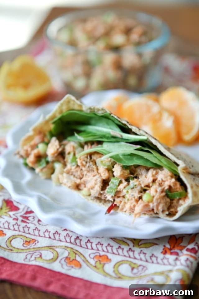 Half a pita bread stuffed with flavorful blackened salmon salad and fresh spinach leaves, perfectly portioned for a healthy, quick lunch.
