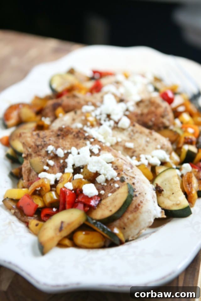 A beautifully plated dish of balsamic chicken with colorful sweet peppers, vibrant zucchini, and corn, finished with crumbled feta cheese. Perfect for a quick, healthy summer meal.