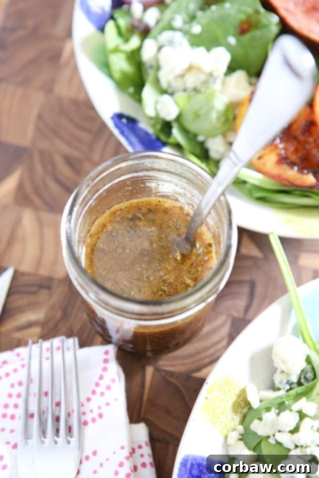 Close-up shot of a small jar filled with freshly made honey balsamic vinaigrette, with a vibrant salad in the soft focus background, highlighting the homemade freshness.